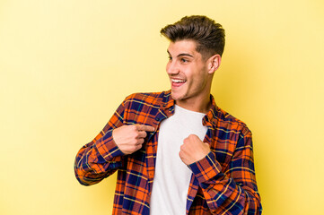 Young caucasian man isolated on yellow background surprised pointing with finger, smiling broadly.