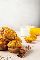 Pumpkin muffins with spices and seeds and milk on light background. Copy space. Autumn, halloween, thanksgiving baking concept. Selective focus.