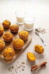Pumpkin muffins with spices and seeds and milk on light background. Copy space. Autumn, halloween, thanksgiving baking concept.