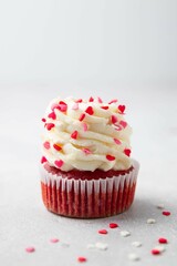 Red velvet cupcake with cream cheese frosting and red hearts sprinkles on the top. Valentine's Day concept. Selective focus.
