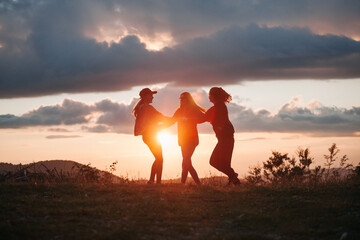 three happy young girls dance together holding hands