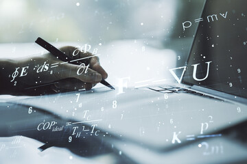 Double exposure of creative scientific formula concept with hand writing in notebook on background with laptop, research and development concept