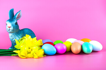 rabbit bouquet of flowers and painted multicolored easter eggs on a pink background