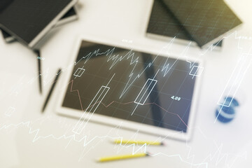 Multi exposure of abstract creative financial graph and modern digital tablet on background, top view, forex and investment concept