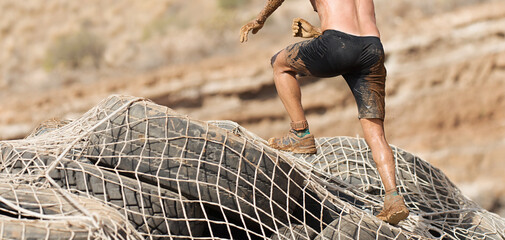 Mud race runners.The participante overcoming the obstacle made of tires