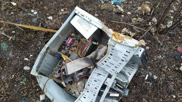 Old broken PC computer on a junkyard - components inside deformed case of vintage personal electronic device, thrown away, laying on the ground, ready to be recycled. Obsolete information technology.