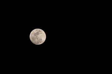 Full moon shining over dark black sky at night
