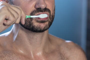 Close up of young man with toothbrush cleaning his teeth. Health care, dental hygiene and beauty concept