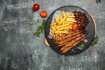 Bbq meat on wooden skewers with fries and vegetables, Georgian cuisine. hearty lunch or dinner,...