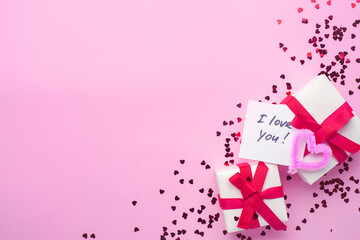 White boxes with gifts on a pink background. St. Valentine's Day. Fluffy hearts. Concept of love and spring. Top view, background, copy space. Lettering: I love you