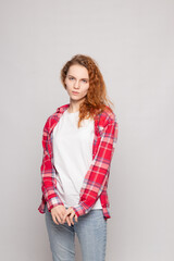 a young girl in a plaid shirt stands sad against a light background