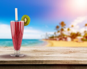 The photo of a strawberry smoothie. The glass is placed on the wooden desk