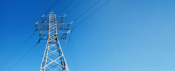 High-voltage power lines over blue sky, high voltage electric transmission tower, panoramic layout