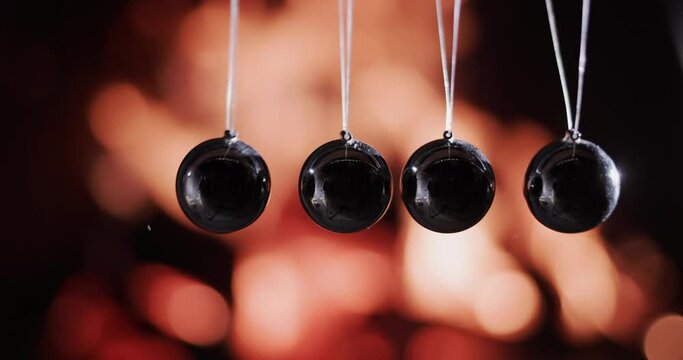 Balls in Newton's pendulum hit the background of fire. Slow-motion video