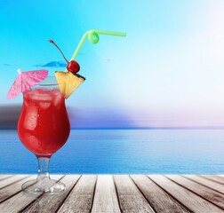 The photo of a strawberry smoothie. The glass is placed on the wooden desk