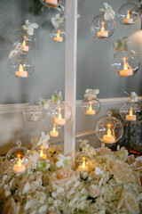 A closeup shot of hanging glass balls with candles for decoration Wedding ceremony decorated with lit candles inside of round glass spheres White flowers bouquet below