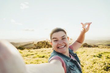 Caucasian woman taking a selfie while hiking in the mountains