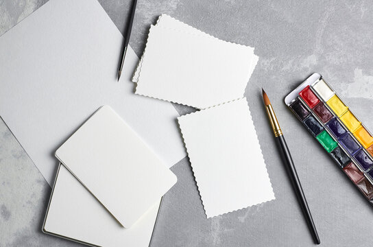 Blank paper cards, watercolor palette and paint brushes. Art mockup, painting and drawing presentation.