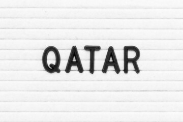 Black color letter in word qatar on white felt board background