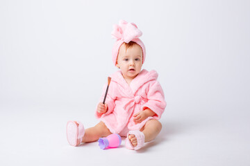 Cute little baby girl in pink terry with makeup isolated on a white background, repeats the behavior of mom