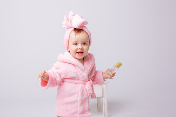 Cute little baby girl in pink terry with makeup isolated on a white background, repeats the behavior of mom