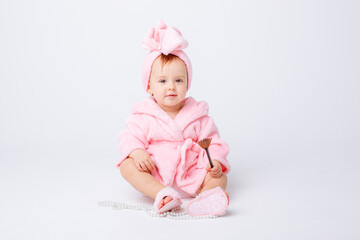Cute little baby girl in pink terry with makeup isolated on a white background, repeats the behavior of mom