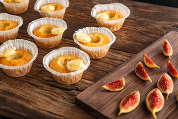 Homemade cupcakes with fresh figs on wooden background. Process of cooking vanilla muffins with filling.