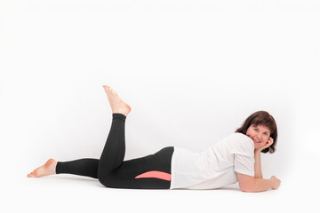 Fototapeta na wymiar Portrait of cheerful young girl with curvy figure lying on white background after sports workout.