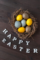 Birds nest and colorful eggs. Happy Easter lettering. Vertical frame
