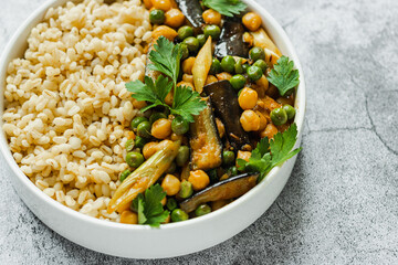 Eggplant chickpeas peas vegetarian vegan curry with bulgur in a pan on a gray background, top view. Indian cuisine. healthy food. vegan. plant base.