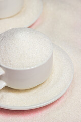 Overflowing cups with sugar on a pink background. Excessive sugar intake