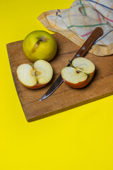 Apples on a yellow background. Halves of an apple on a wooden board.