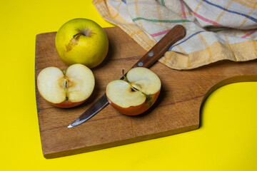 Apples on a yellow background. Halves of an apple on a wooden board.