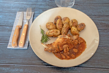 new potatoes with mushroom rabbit in a plate on a gray background