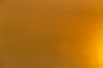 Abstract photo of surface of water with warm light tone on the morning time.