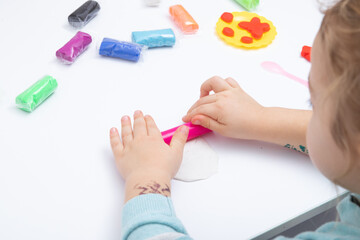 Obraz na płótnie Canvas Childrens hands play dough for children's creativity. Board game for the development of fine motor skills