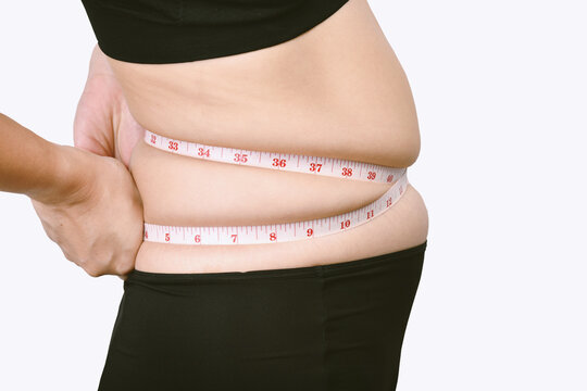 Fat woman measuring her belly fat, Overweight woman check out her obesity, Woman muffin top waistline.
