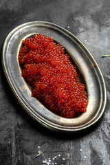 Delicious red caviar in black bowl on a concrete background. banner, menu, recipe. selective focus, place for text