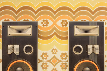 Two vintage stereo speakers in front of retro seventies flower wallpaper - obrazy, fototapety, plakaty