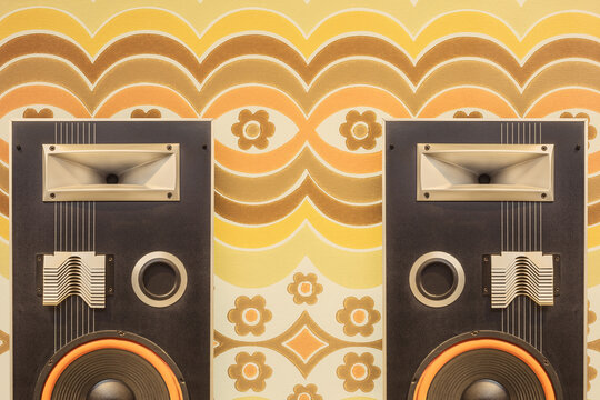 Two vintage stereo speakers in front of retro seventies flower wallpaper