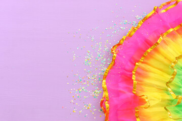 Image of colorful carnival dress over purple background. view from above