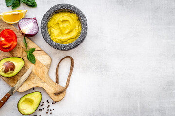 Homemade guacamole avocado dip in mortar with ingredients