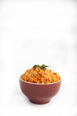 Jollof rice with parsley in a ceramic cup on a white background. National cuisine of Africa. Copy spaes.