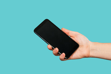 Mobile phone with black screen in female hand isolated on a trendy blue background. Blank with an...