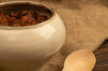 Stewed beans with meat in a small pot. A traditional rustic dish. Close-up, selective focus.
