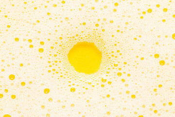 Shampoo foam on a yellow background. Round empty space for text.