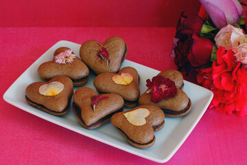 Heart shaped chocolate macaron cookies with pressed edible flowers for Valentines Day
