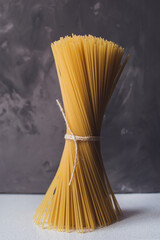 Yellow long raw spaghetti on a gray background. Italian pasta. Food background concept. Beautiful ingredients.