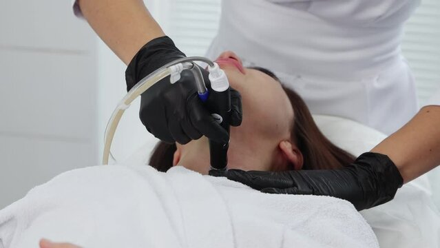 Face massage - young brunette woman having an electric massage procedure on her neck