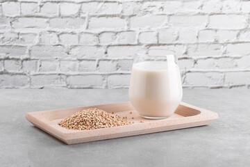 Vegan non diary buckwheat milk in glass on a wooden plate with buckwheat groats on a grey stone table. Vegan buckwheat drink is plant based alternative milk . Veggies healthy milk product